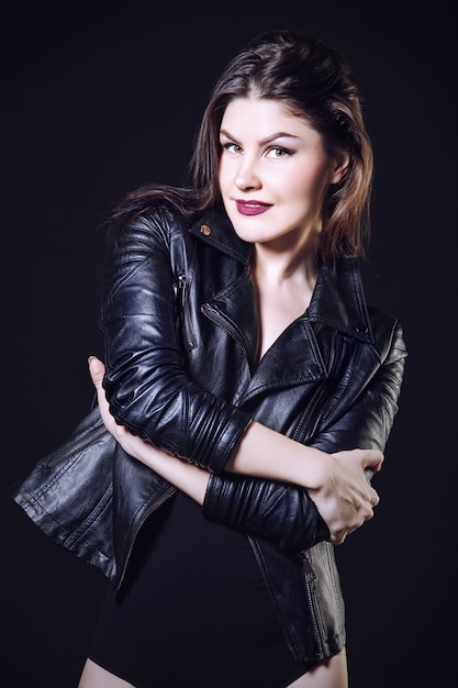 Beautiful young woman model in Studio in lingerie and leather jacket on a dark background