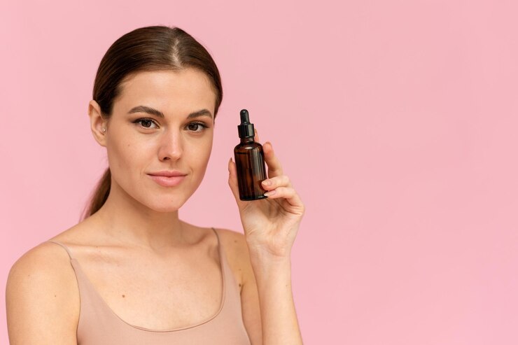 A beautiful young woman moisturizes her skin with a serum. Caring for the skin. Essential Oil For Anti-Aging Therapy