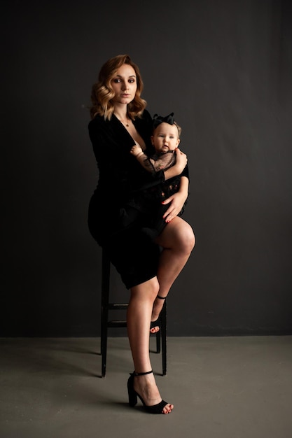 Beautiful young woman mother of little baby on dark background