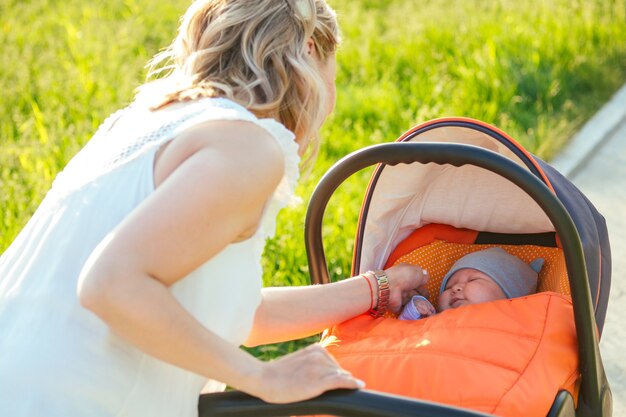 Foto bella e giovane donna madre che si prende cura del bambino in un passeggino