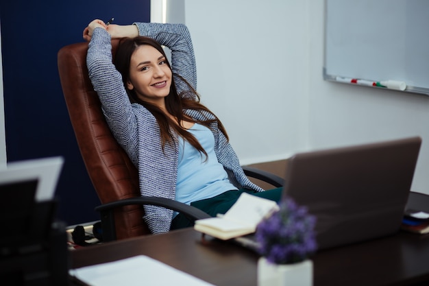 Beautiful young woman in office arms folded