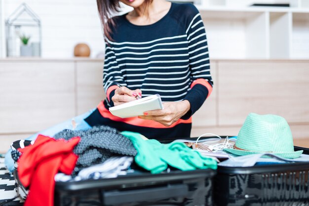 大きなスーツケースに荷物を詰め込んだ美しい若い女性。旅行準備のコンセプト