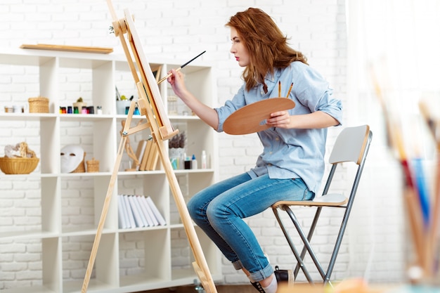 Beautiful young woman painter at work