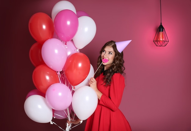 Beautiful young woman in party cap with air balloons