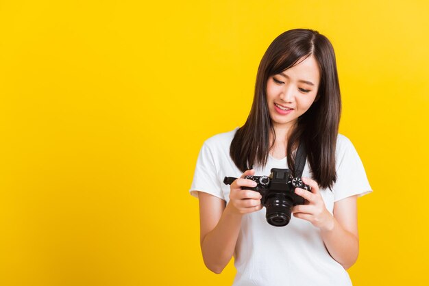 Beautiful young woman photographing against yellow background