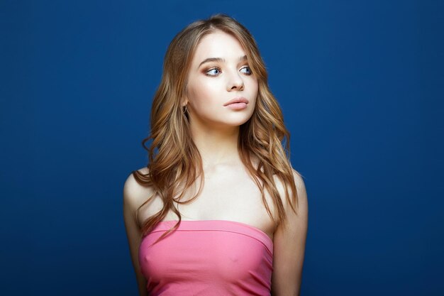 Beautiful young woman in pink top over blue background