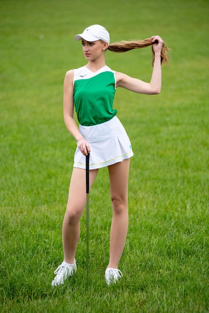 Beautiful young woman playing golf on the green grass