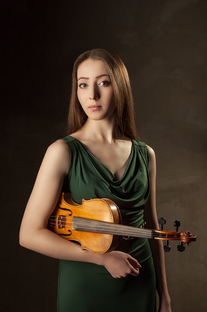 Bella giovane donna che suona il violino su sfondo nero