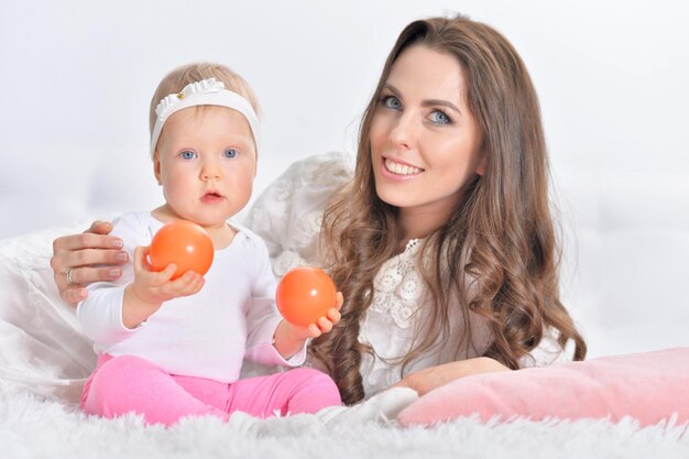 Beautiful young woman playing with cute little daughter