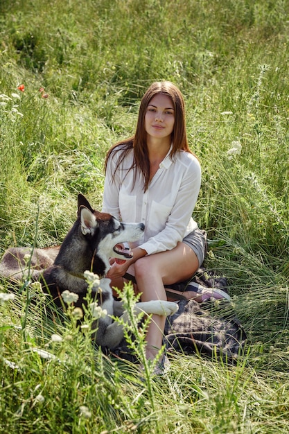 Bella giovane donna che gioca con il cane husky divertente all'aperto al parco