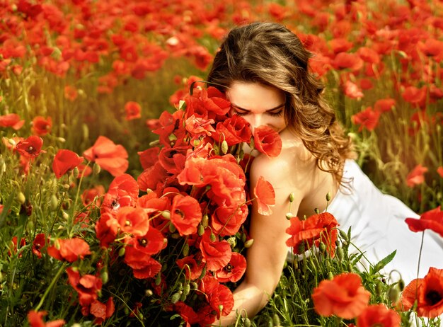 Bella giovane donna in campo di papaveri con capelli volanti