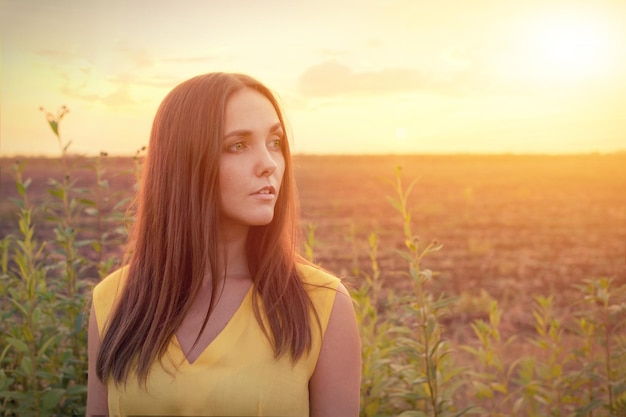 Beautiful young woman portrait against sunset evening field woman relaxing getaway