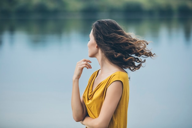 Beautiful young woman portrait near the lake in a bright dress