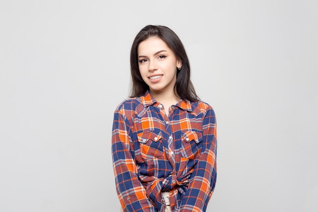 Beautiful young woman portrait Portrait of a beautiful smiling brunette in a plaid shirt on a whitegray