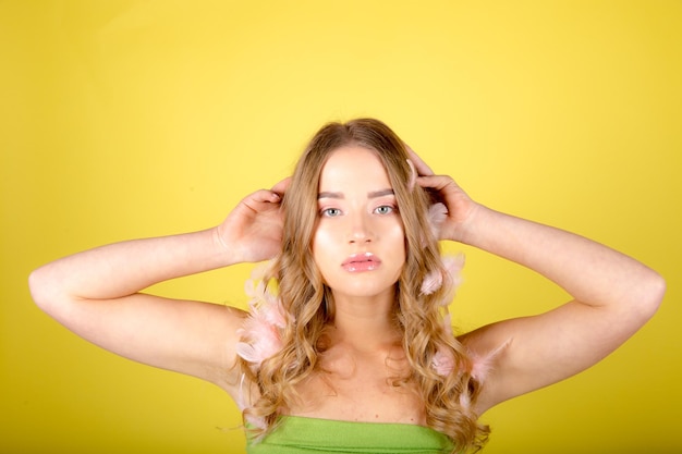 Beautiful young woman posing isolated over yellow wall background with feather