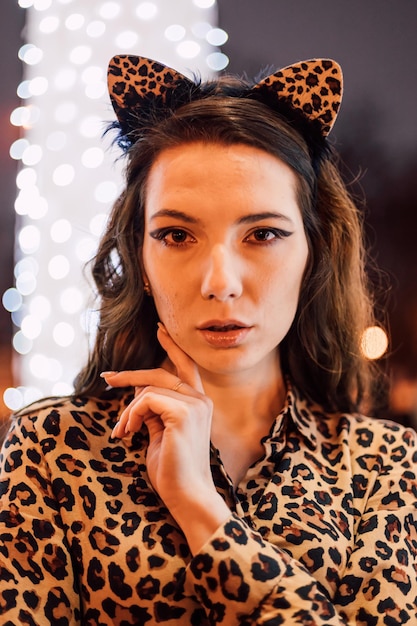 Beautiful young woman posing in a leopard print dress on a winter evening in a city park