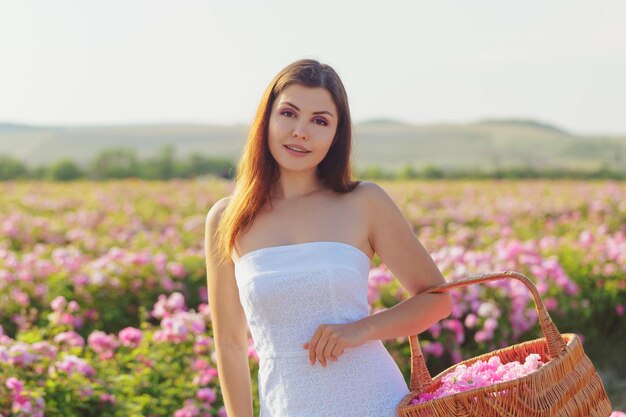 Beautiful young woman posing near roses in a garden.