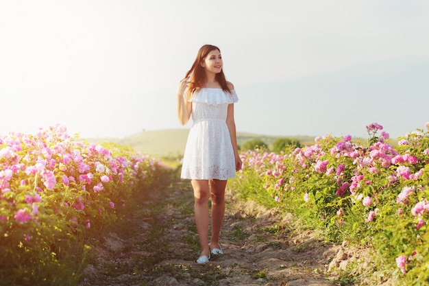 Beautiful young woman posing near roses in a garden,