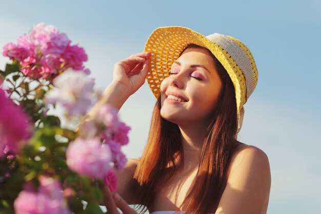 Beautiful young woman posing near roses in a garden.