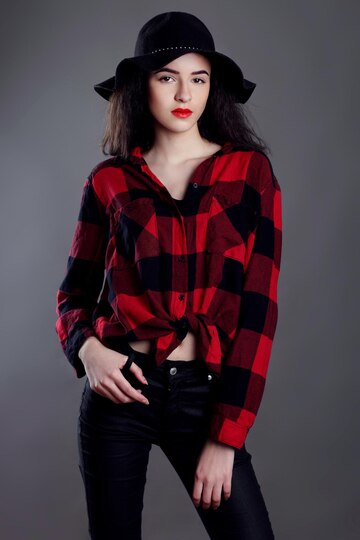 Premium Photo  Beautiful young woman posing in red plaid shirt and black  hat isolated over grey background