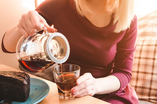 La bella giovane donna versa il caffè nella tazza