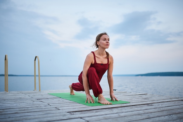 Beautiful young woman practices yoga asana Virabhadrasana