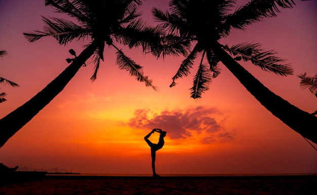 Beautiful young woman practices yoga at the beach. Early morning exercise. Sunrise