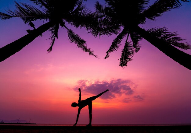 Beautiful young woman practices yoga at the beach. Early morning exercise. Sunrise