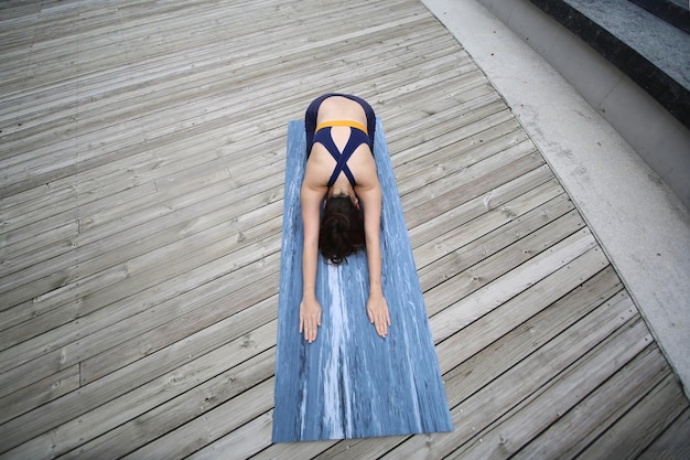 Beautiful young woman practicing yoga on wooden terrace