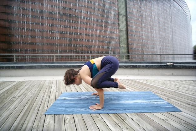 Beautiful young woman practicing yoga on wooden terrace