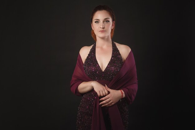 Beautiful young woman in purple dress posing in studio. Classic make-up for the evening event