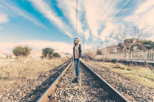 Bella giovane donna sui binari ferroviari.