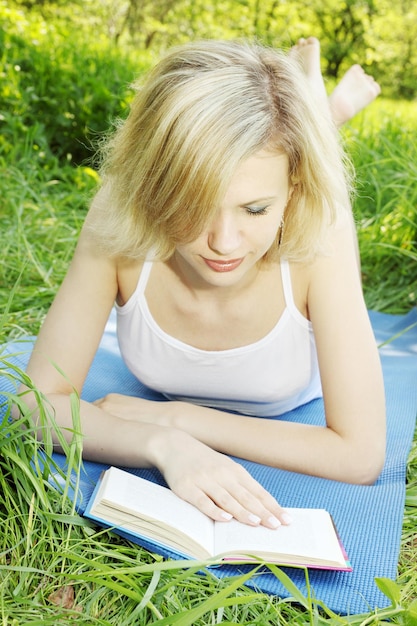 Beautiful young woman reading a book on nature