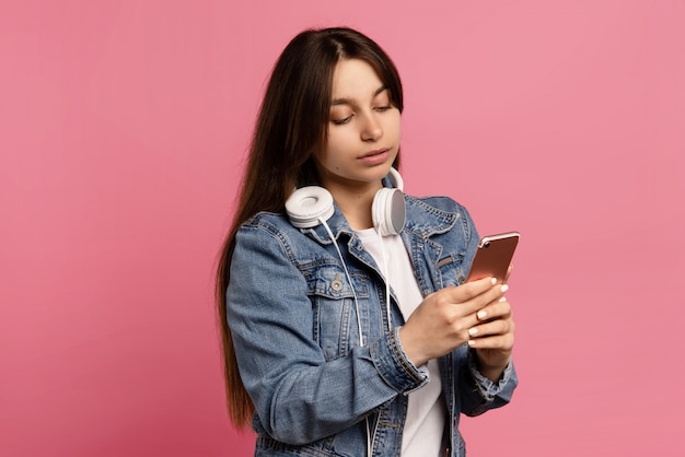 Beautiful young woman receives funny sms isolated on pink