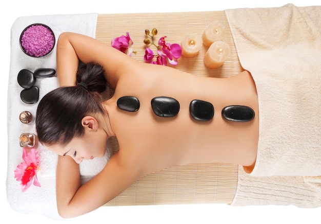 Beautiful young woman receiving hot stone massage at salon spa