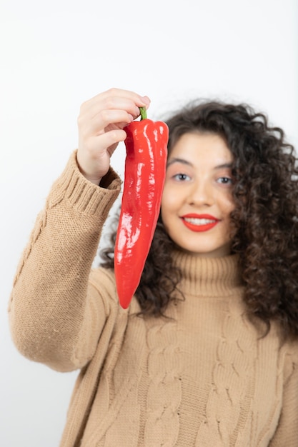 Beautiful young woman in red lipstick holding red chili pepper.