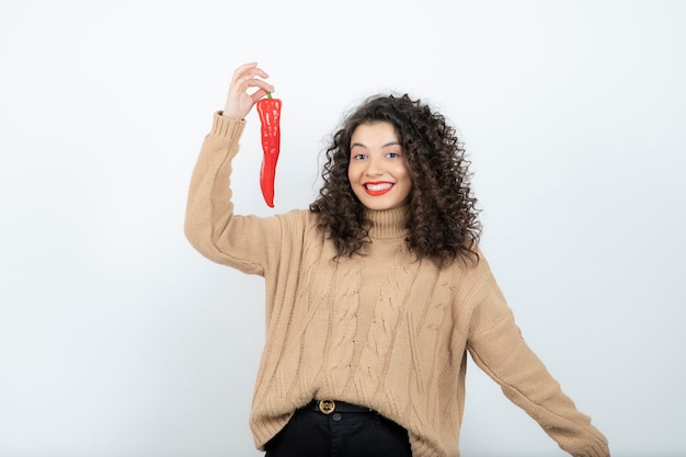 赤唐辛子が立っている赤い口紅の美しい若い女性。