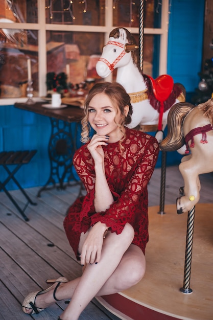 Красивая молодая женщина радуется возле карусели с лошадьми. Рождество.