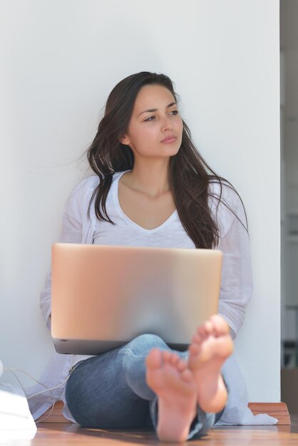 beautiful young woman relax and work on laptop computer while listening music on heaphones and read book at home