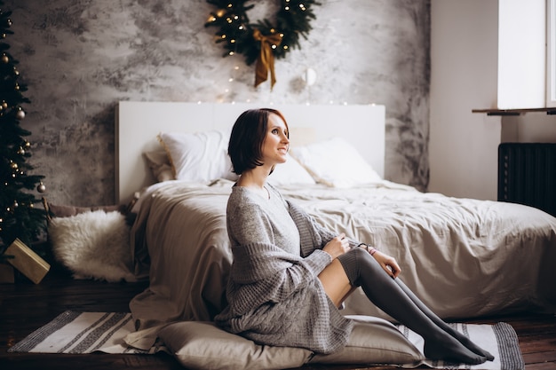写真 クリスマスツリーの近くのベッドでリラックスした美しい若い女性
