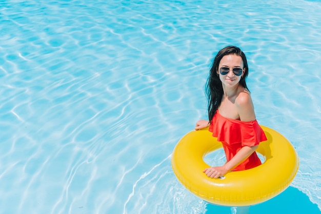 Bella giovane donna che si distende nella piscina.