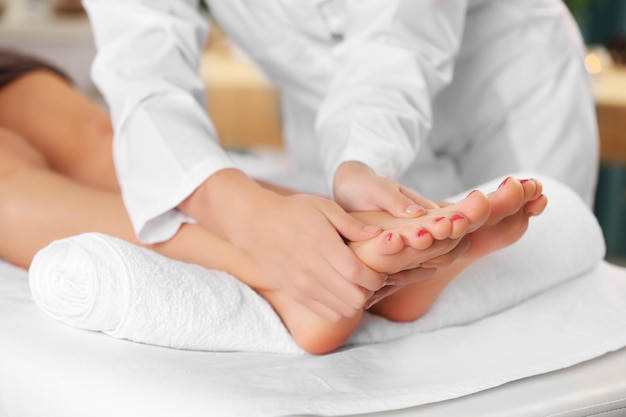 Foto bella giovane donna che si distende con massaggio alle gambe presso il centro termale di bellezza