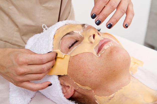 Beautiful young woman remove  facial mask  in a beauty center