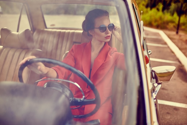 Beautiful young woman in retro car