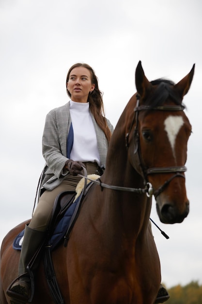 Beautiful young woman riding a horse on the field Sideways to the camera Freedom joy movement