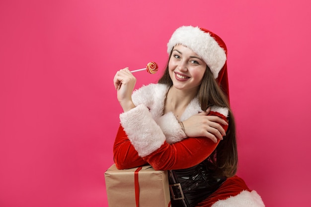 Bella giovane donna in costume di babbo natale sullo sfondo rosso.