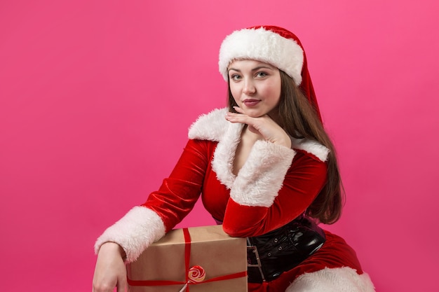 Beautiful young woman in Santa Claus costume against the red background.