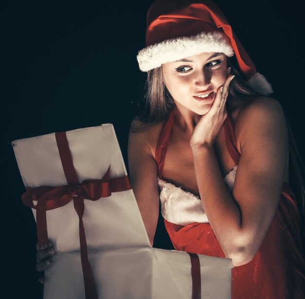 Beautiful young woman in santa claus costume with christmas shopping