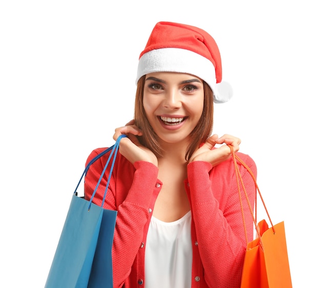 Beautiful young woman in Santa Claus hat and with bags on white background. Christmas shopping concept