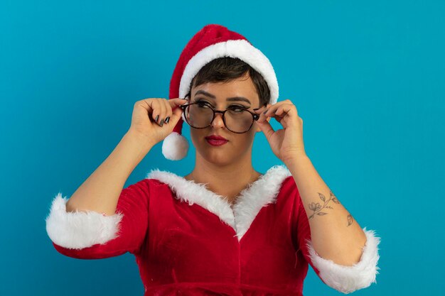 Beautiful young woman in santa claus outfit and hat wearing glasses and christmas theme